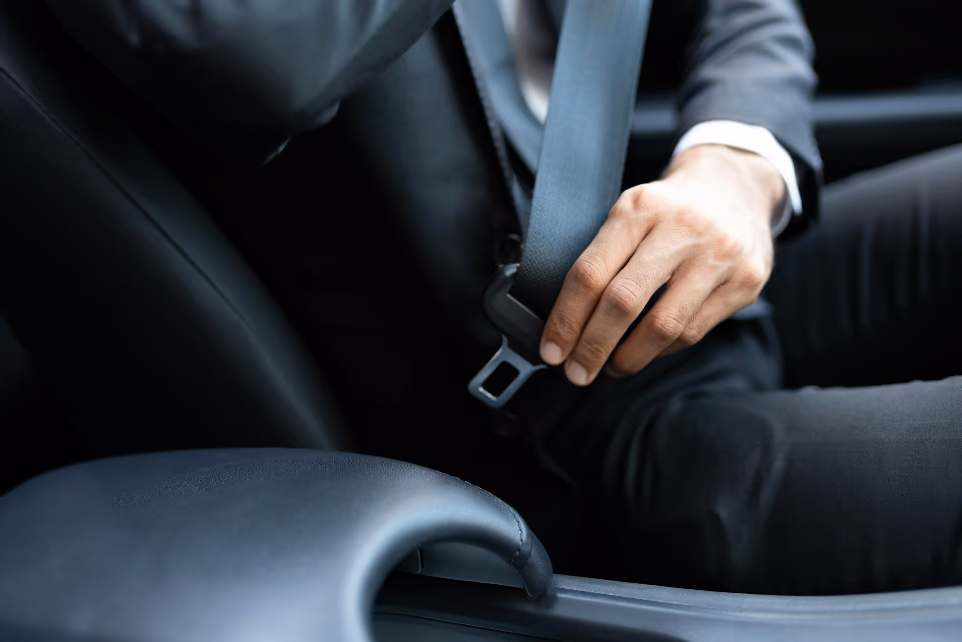 A corporate in a suit fastening their seatbelt inside a luxury vehicle, preparing for a private transfer journey.