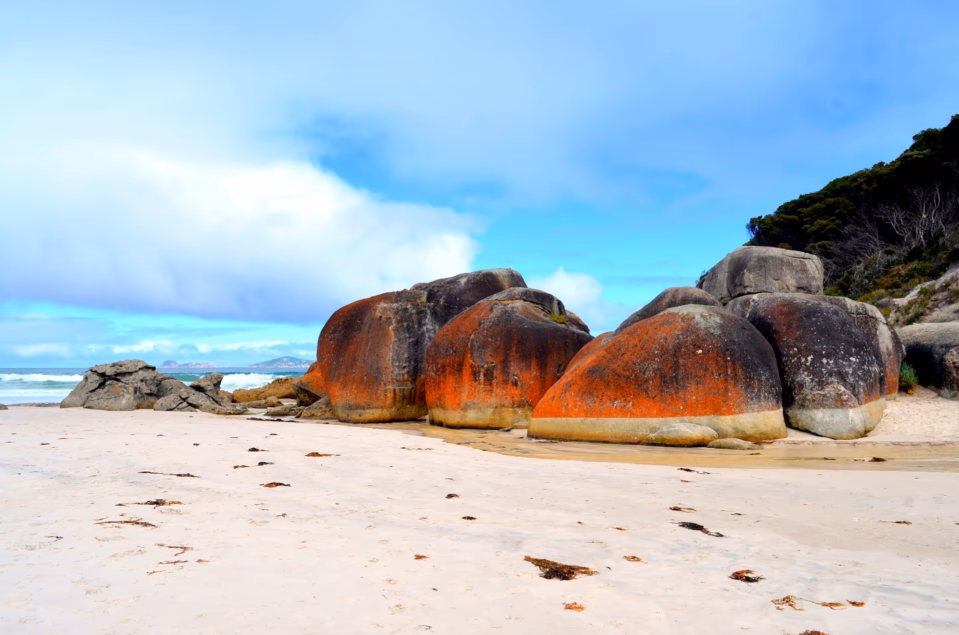 Wilsons Promontory, Victoria, featuring striking orange-hued boulders on a sandy beach.