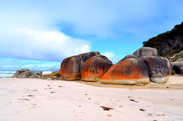 Wilsons Promontory, Victoria, featuring striking orange-hued boulders on a sandy beach.