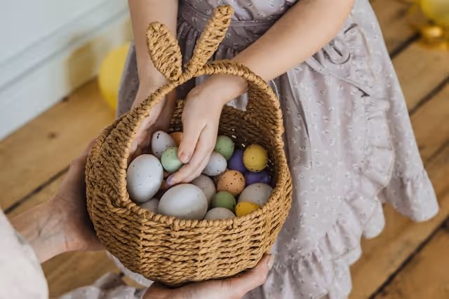 A child holds a woven Easter basket filled with colourful eggs, symbolising Easter celebrations and festive gatherings.