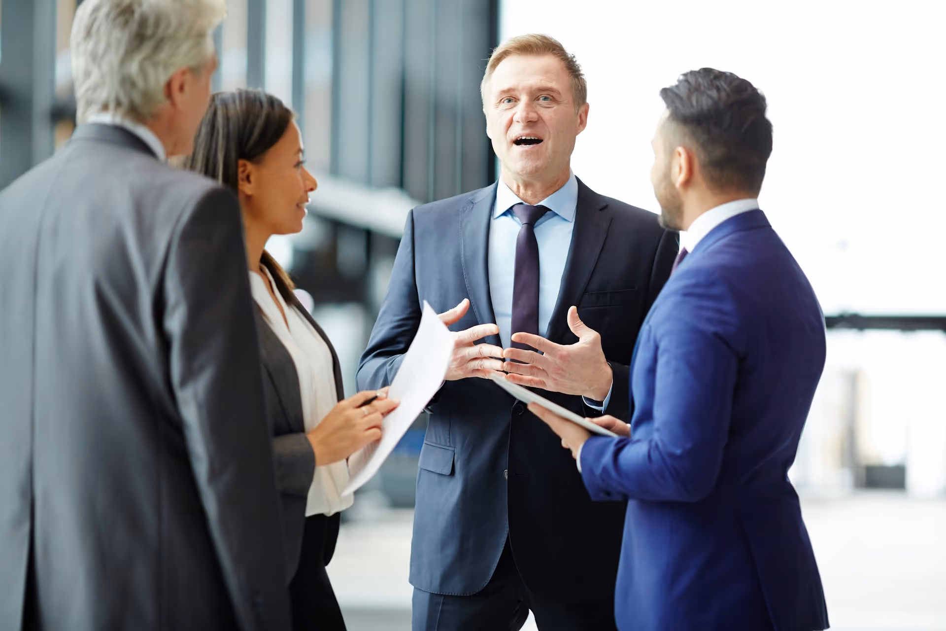 A group of business professionals in formal attire engaged in a discussion