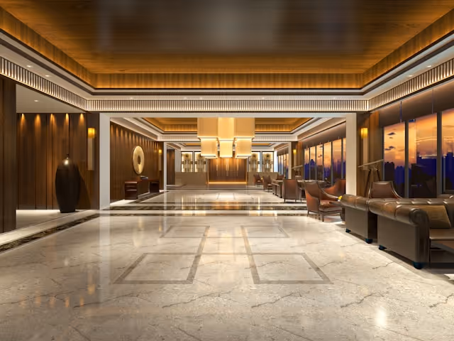 A luxury hotel lobby with warm lighting, marble flooring, stylish leather seating, and wooden accents.