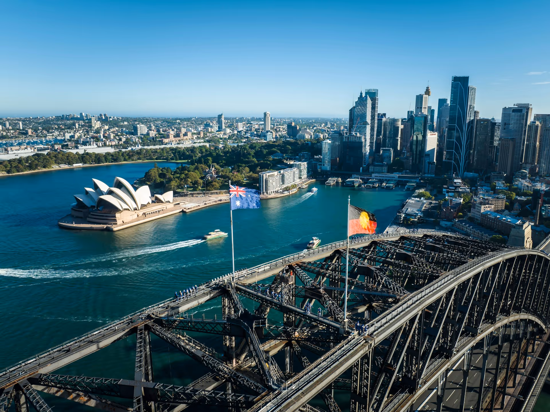 Aerial view of the Sydney Opera House, Harbour Bridge, and city skyline on a clear day, capturing the iconic landmarks featured in Sydney HeliTours experiences.