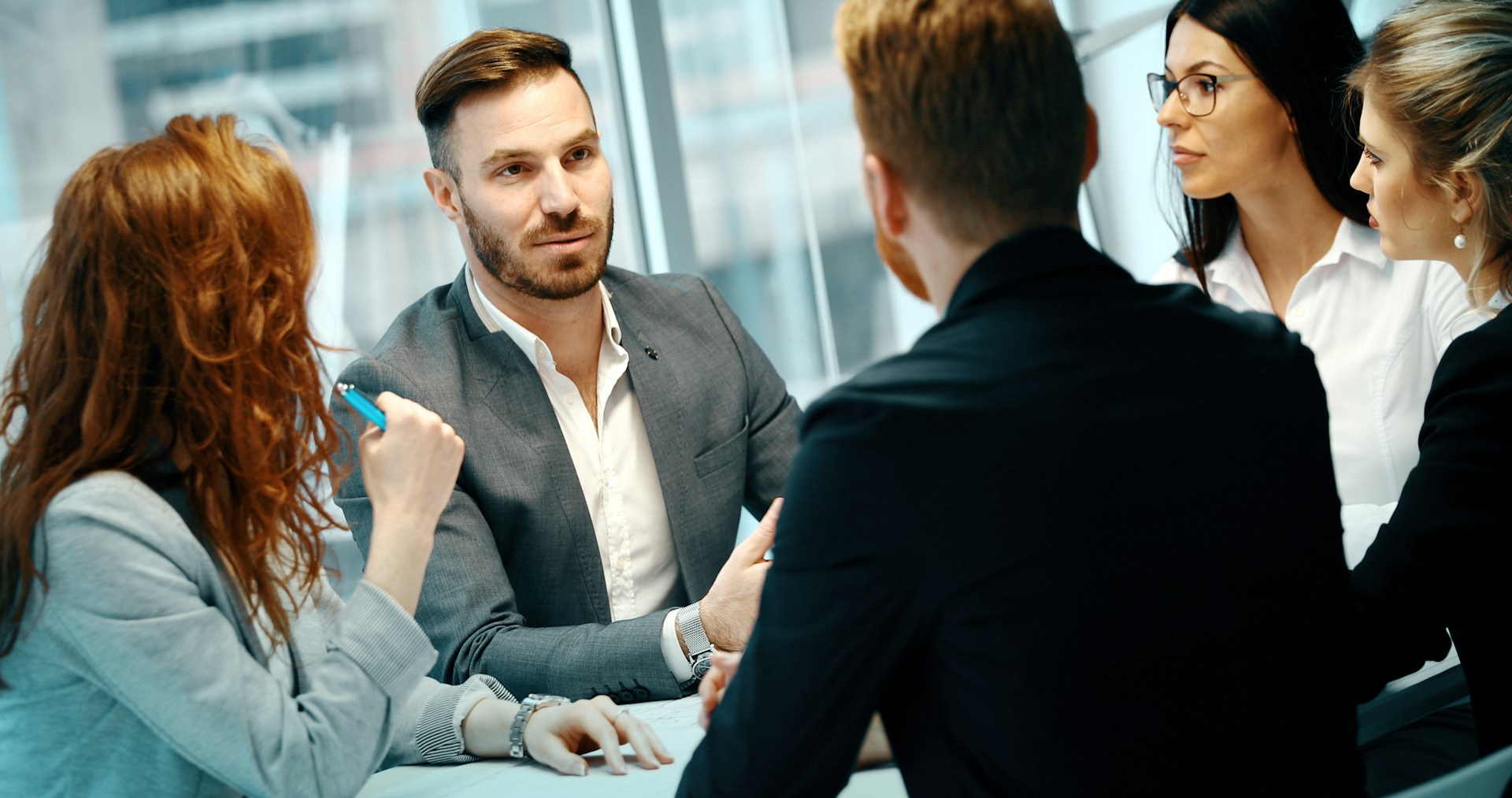 Corporate team in formal business attire engaged in a focused meeting, reflecting the importance of punctual, professional chauffeur services for time-critical executive travel.