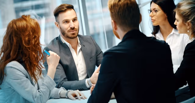 Corporate team in formal business attire engaged in a focused meeting, reflecting the importance of punctual, professional chauffeur services for time-critical executive travel.