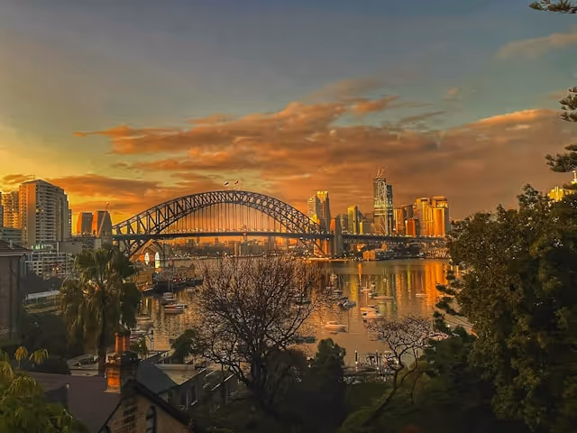 Sunrise over Sydney Harbour Bridge and city skyline, evoking the early morning calm and reliability associated with professional chauffeur airport transfers.