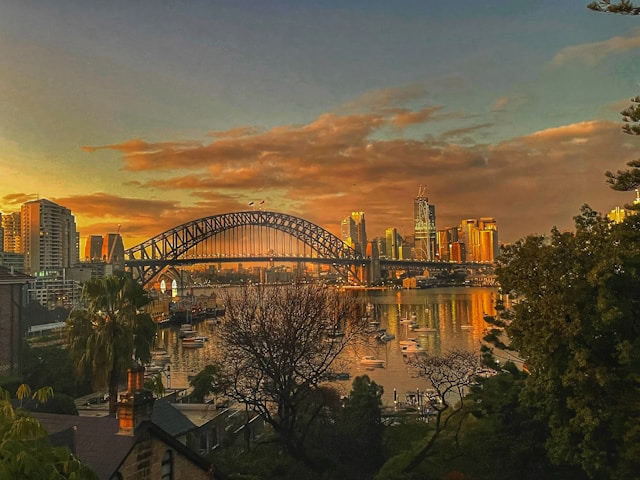 Sunrise over Sydney Harbour Bridge and city skyline, evoking the early morning calm and reliability associated with professional chauffeur airport transfers.
