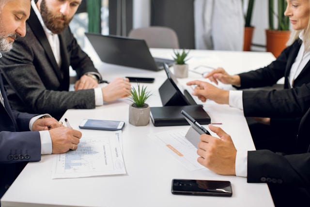 Corporate team meeting around a table with laptops and documents, supporting the theme of professional group planning and business travel logistics in Sydney.