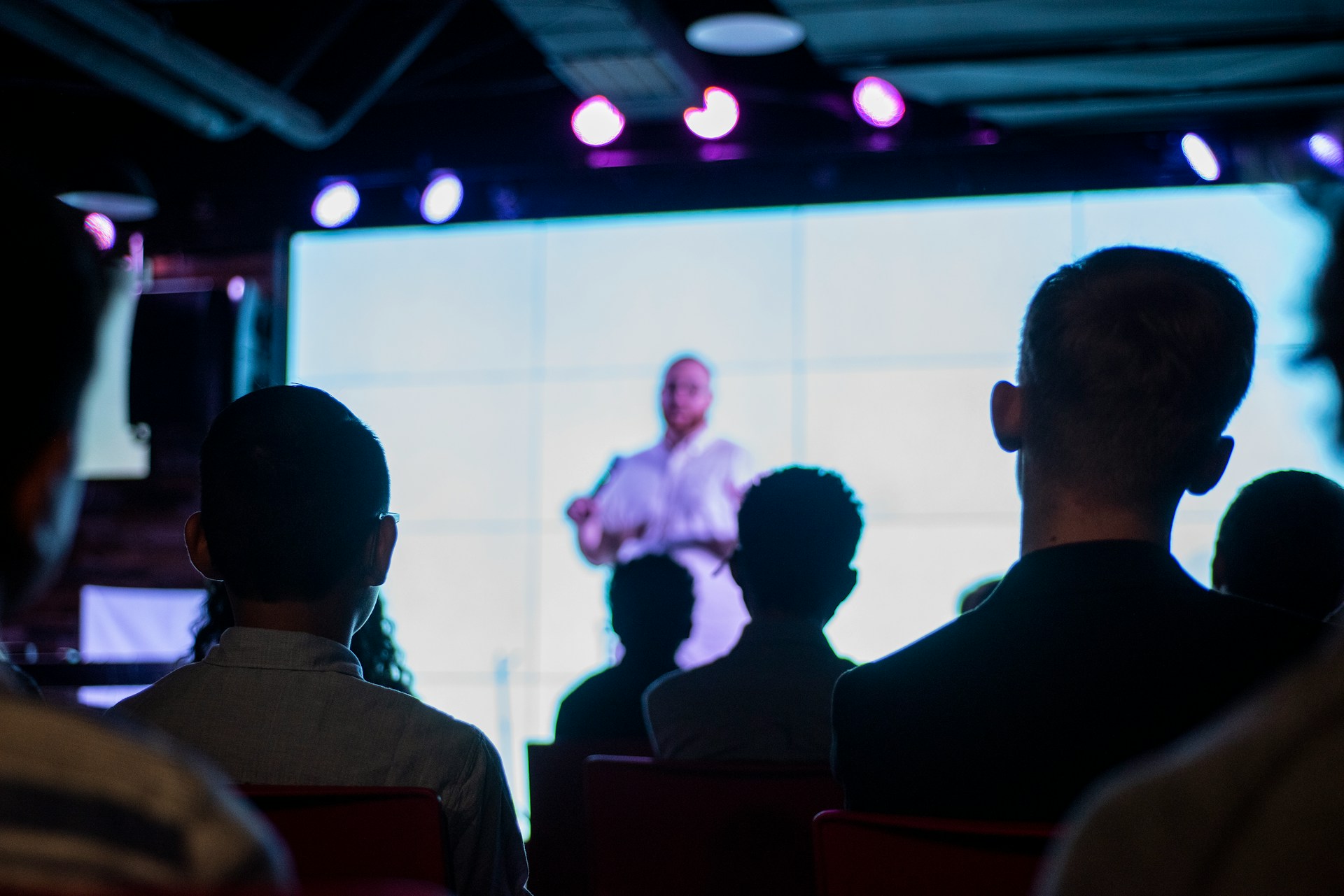 Audience watching a keynote speaker on stage under event lighting.