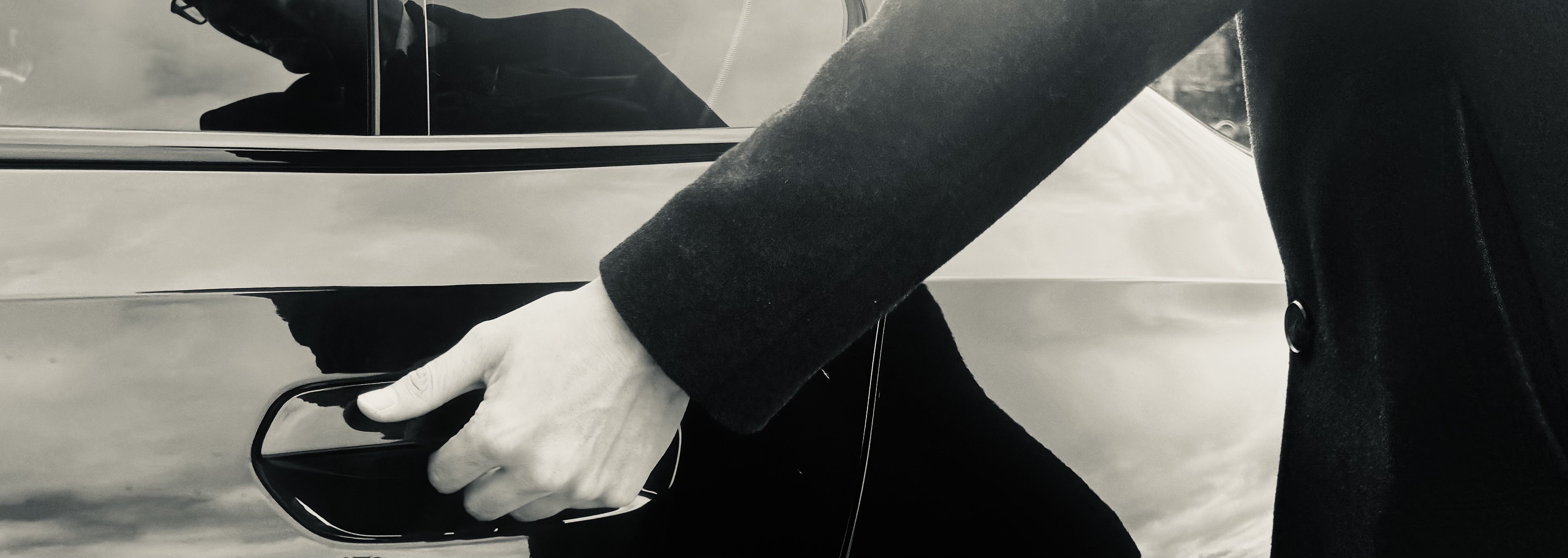 Chauffeur opening the door of a premium vehicle.