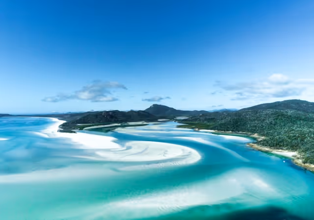 Aerial view of the Whitsundays with white sand swirls and turquoise water, showcasing one of Australia’s most romantic honeymoon destinations.
