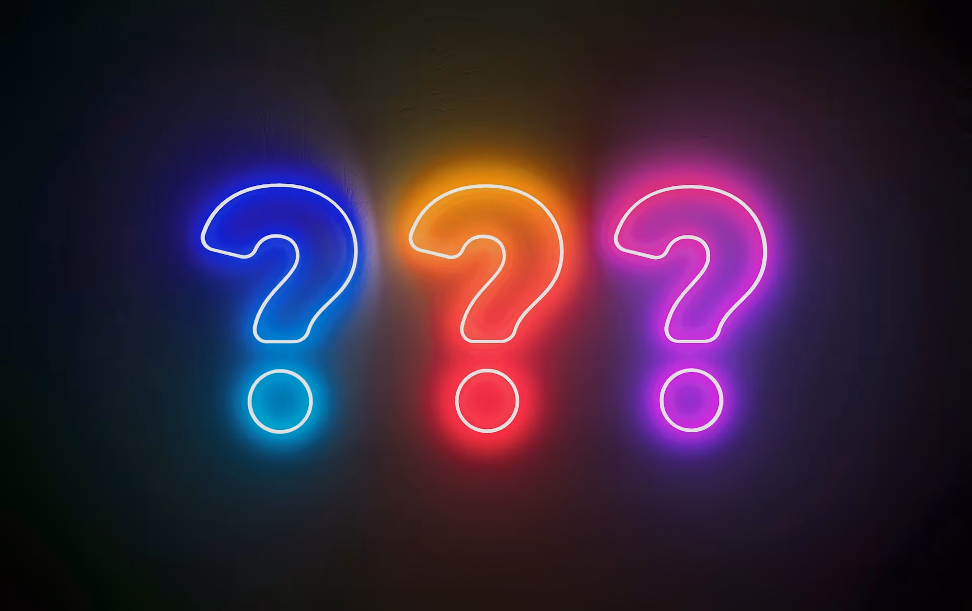 Three neon question marks in blue, orange and pink glowing against a dark background, representing frequently asked questions about chauffeur services.