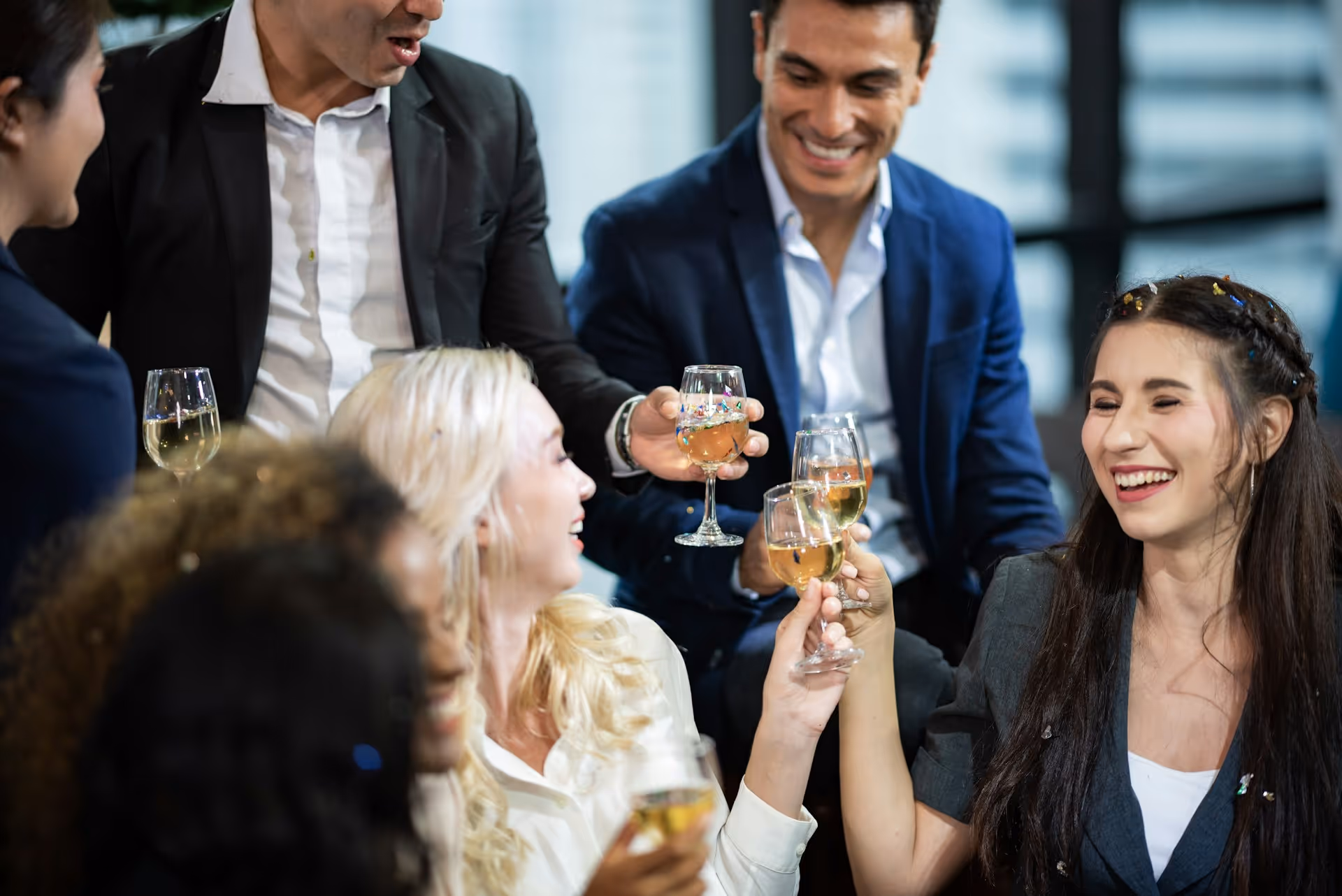 A group of professionally dressed colleagues celebrating with drinks at an end-of-year corporate event.