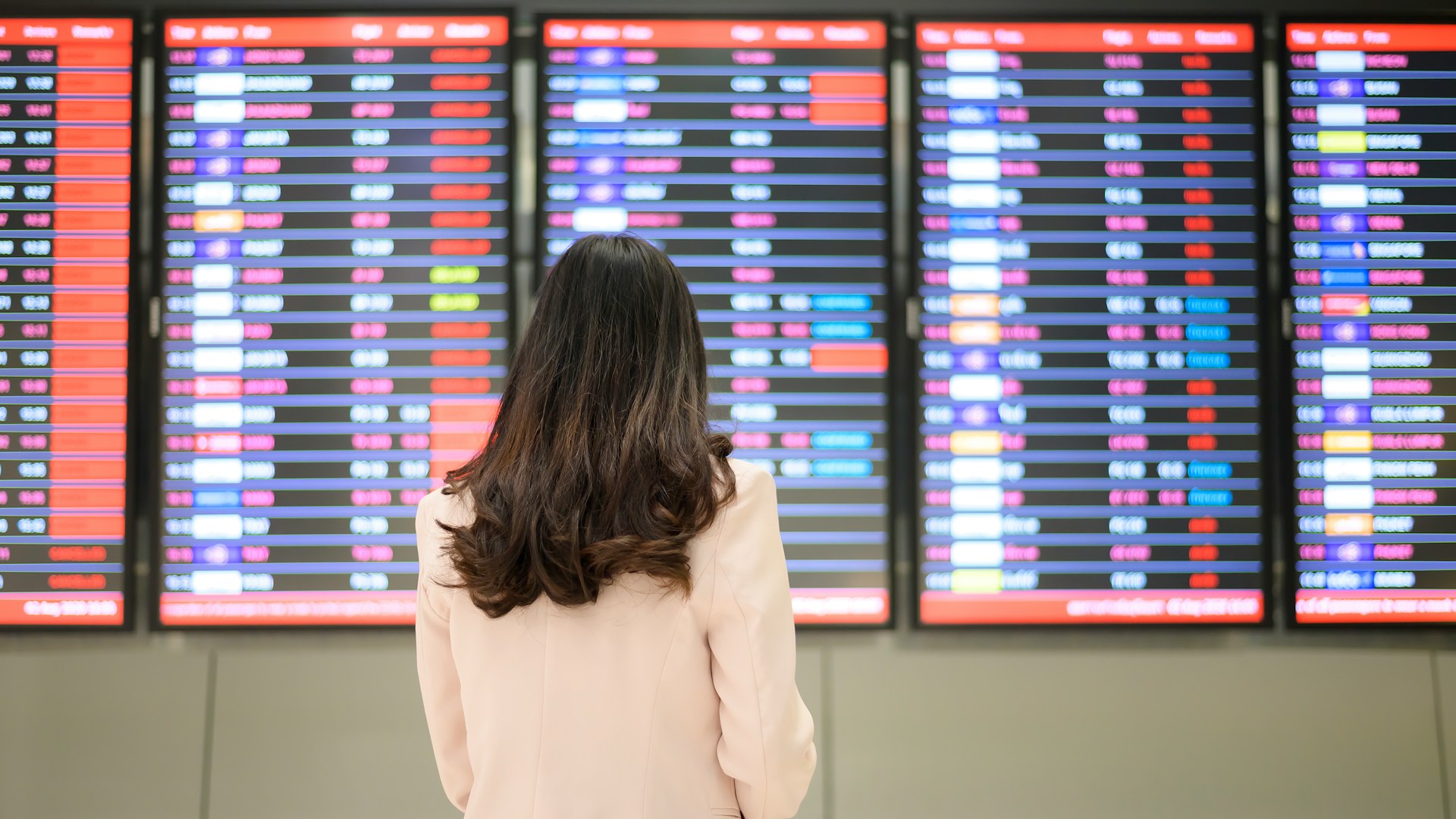 Woman viewing an airport arrivals and departures board.