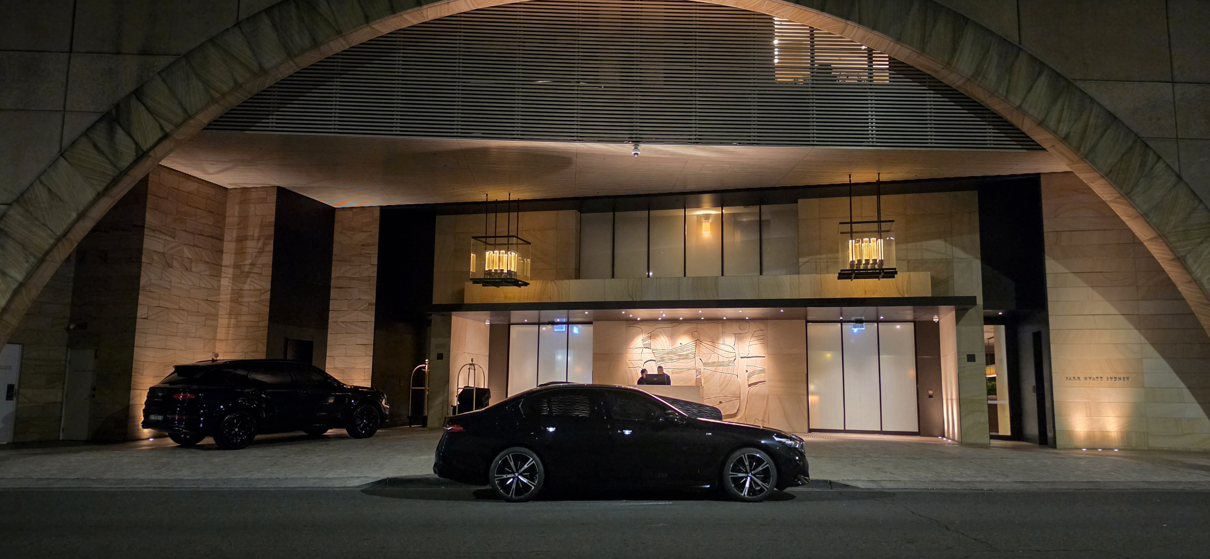 BMW i5 parked outside Park Hyatt Sydney entrance with illuminated hotel façade.