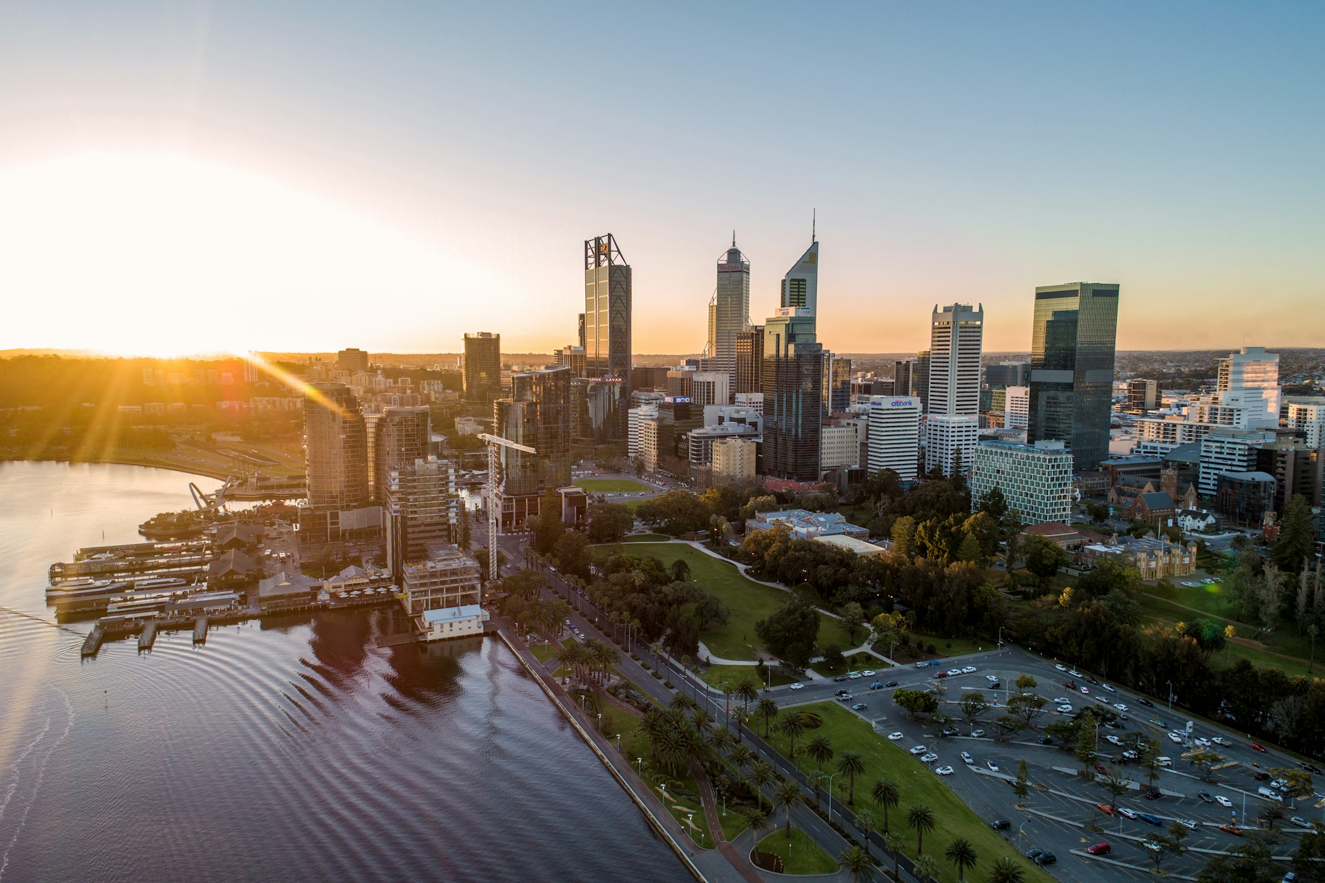 Aerial view of Perth CBD and Elizabeth Quay at sunset, with the Swan River and city skyline.