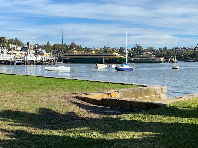 Balmain Ferry Terminal, with moored boats, ferries, and a grassy waterfront park.