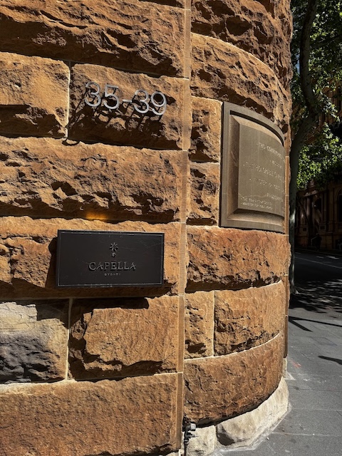 Capella Sydney signage and address displayed on the hotel’s historic sandstone exterior wall.