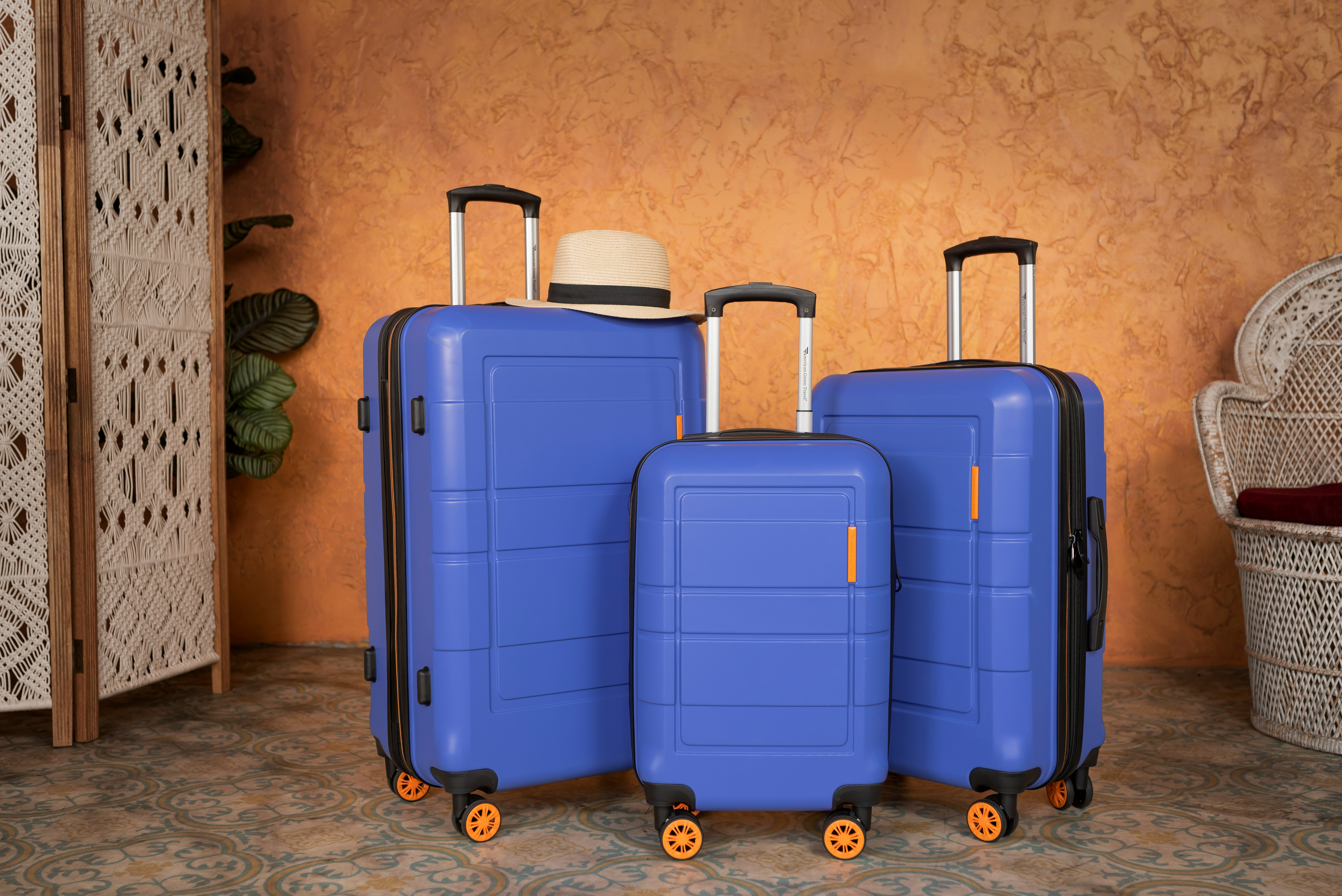 Travelling luggage set with three blue hard-shell suitcases and a sun hat.