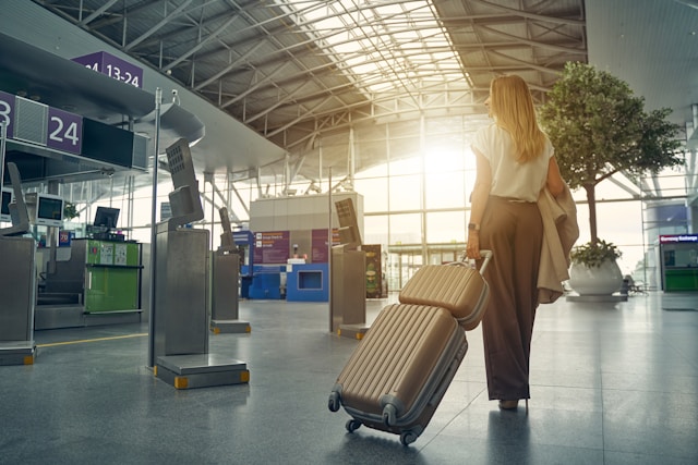 Business traveller walking through an airport terminal with luggage, heading towards the check-in area.
