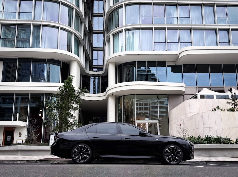 Black BMW i5 chauffeur vehicle parked outside a residential building, ready for a private transfer.