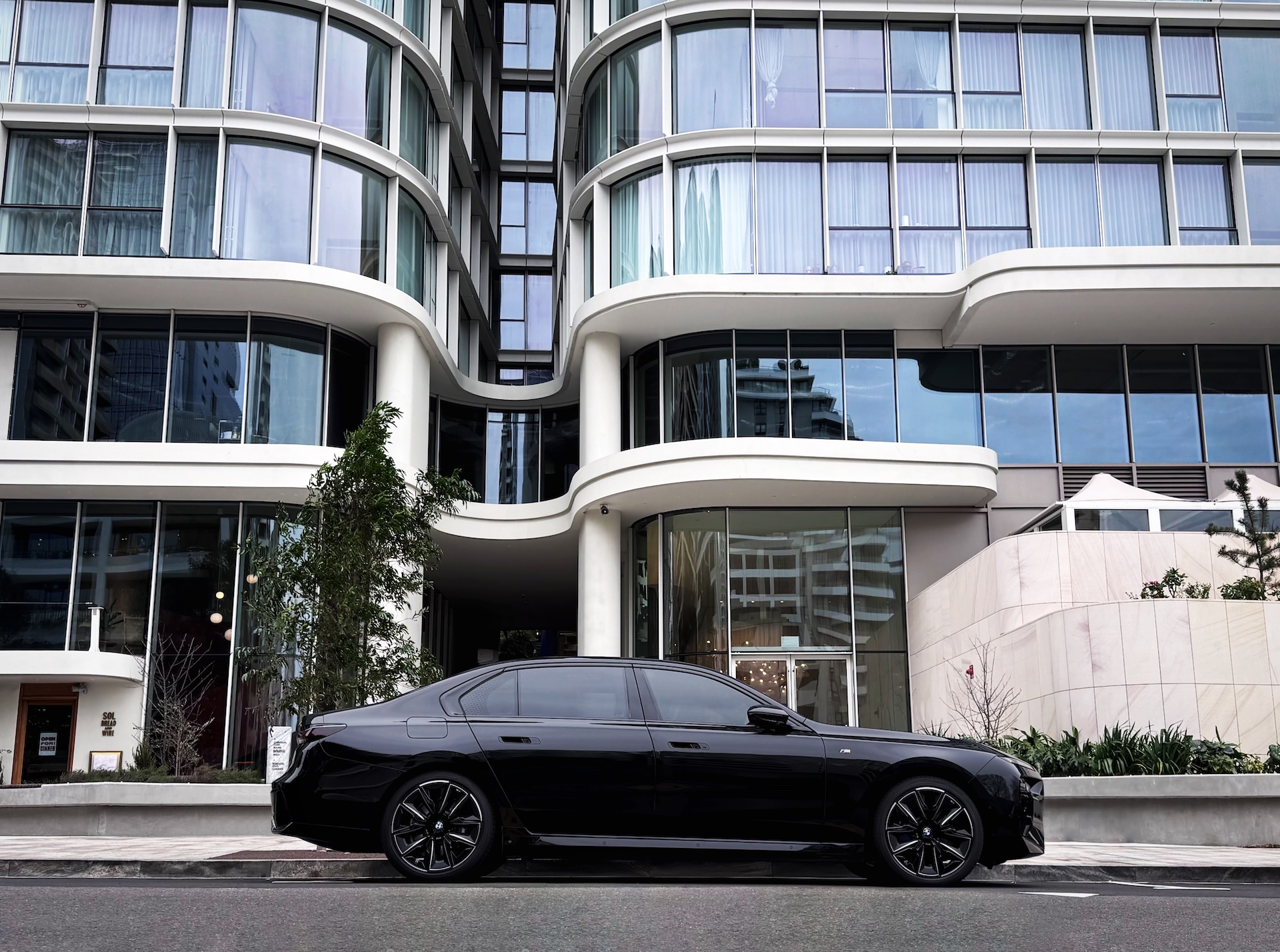 Black BMW i5 chauffeur vehicle parked outside a residential building, ready for a private transfer.