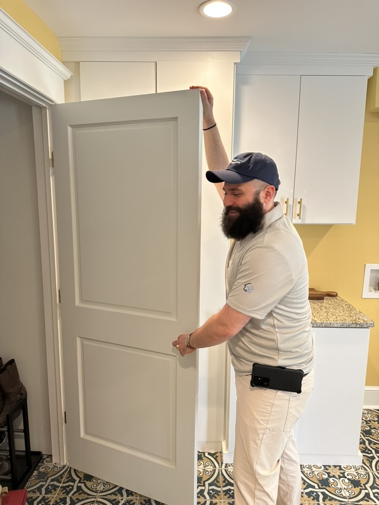 Jacob Ayhan at Happy Homes Inspections inspecting a door and frame and communicating with a customer.