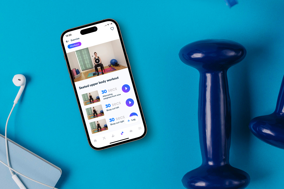 Smartphone displaying a seated upper body workout app screen, placed on blue surface next to white earphones and blue dumbbells.