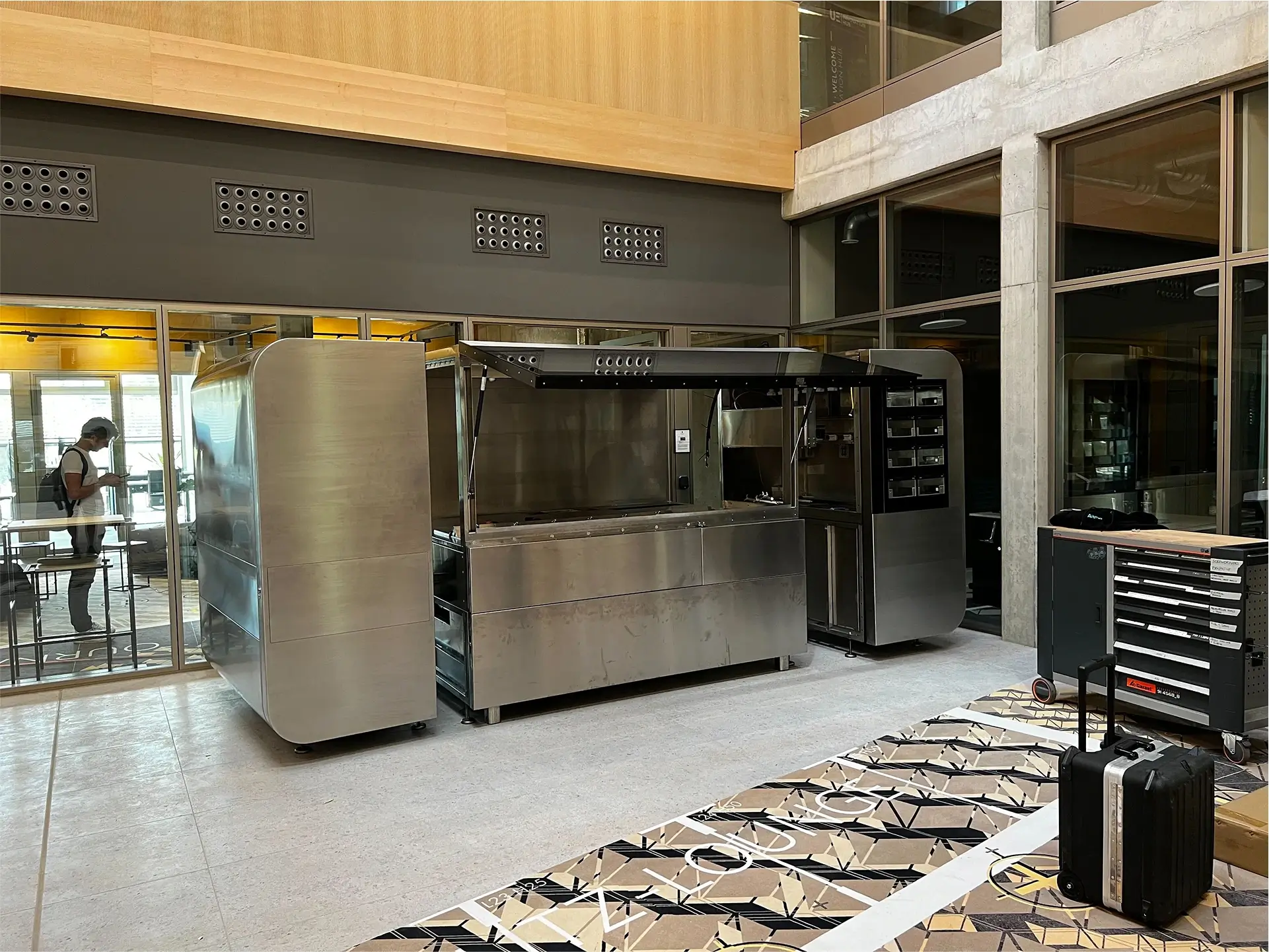 CA-1 Series unit in a research and development setting with tools, suitcases, and a technician nearby, located in a modern office with glass walls and wooden ceiling accents.