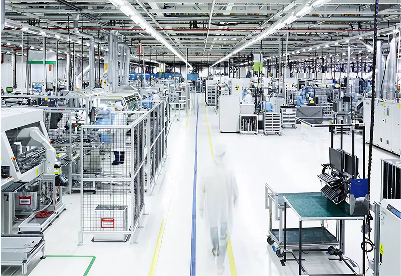 High-tech U.S. production facility with clean white floors, automated machinery, and technicians in white lab coats operating within a bright, modern industrial environment.