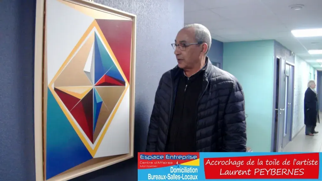 Accrochage d'une toile d'artiste chez Espace Entreprise Montpellier novembre 2018 : personne près de la toile géométrique accrochée dans le couloir