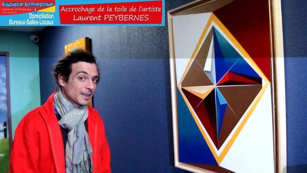 Accrochage d'une toile d'artiste chez Espace Entreprise Montpellier novembre 2018 : personne posant à côté de la toile géométrique colorée