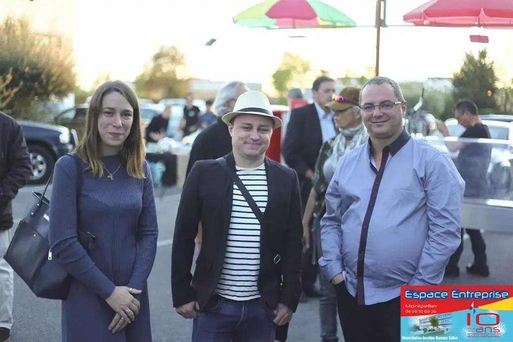 10 ans du centre Espace Entreprise Millénaire à Castelnau-le-Lez en 2018 : invités souriants échangeant sur le parking sous un parasol rouge