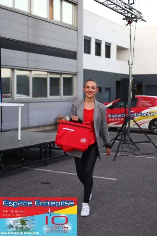 10 ans du centre Espace Entreprise Millénaire à Castelnau-le-Lez en 2018 : personne tenant un sac rouge sur le parking devant les bureaux