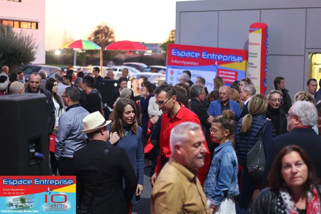 10 ans du centre Espace Entreprise Millénaire à Castelnau-le-Lez en 2018 : foule d'invités en extérieur au crépuscule devant le panneau 10 ans