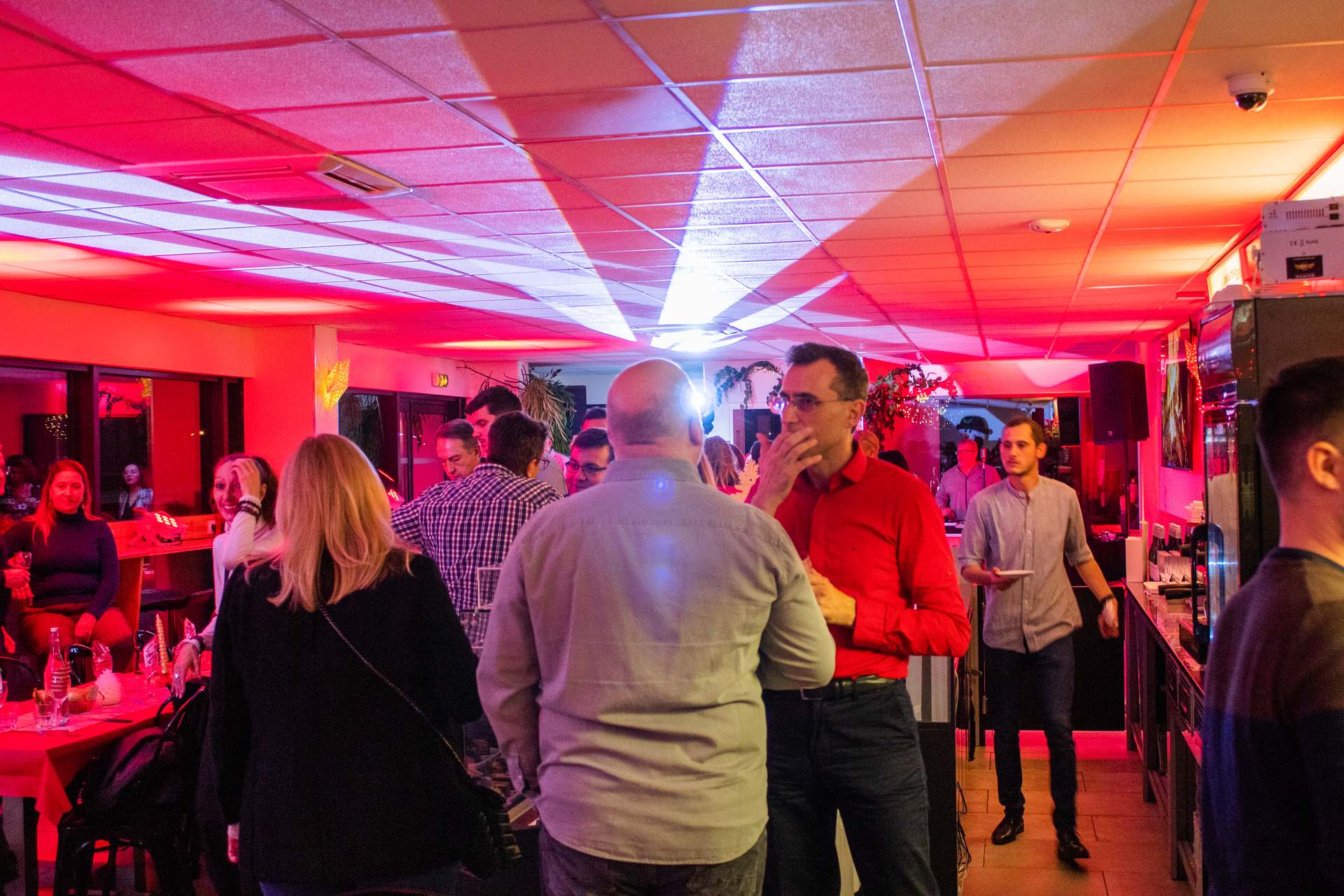 Soirée Prestige 2022 à Montpellier : invités debout échangeant près du bar, éclairage rouge et blanc.