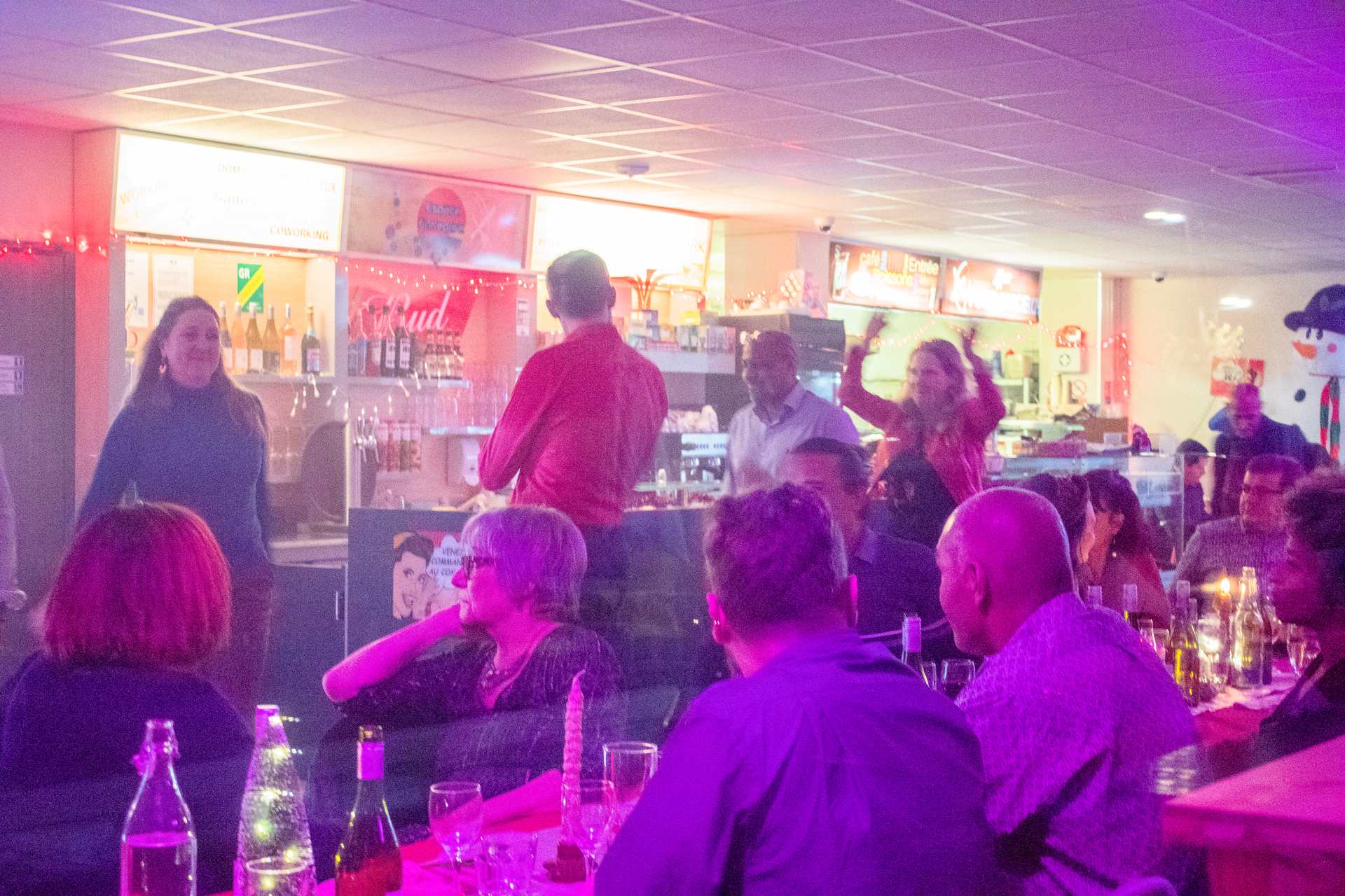 Soirée Prestige 2022 à Montpellier : ambiance au bar, invités rassemblés près du comptoir sous lumière rouge chaude.