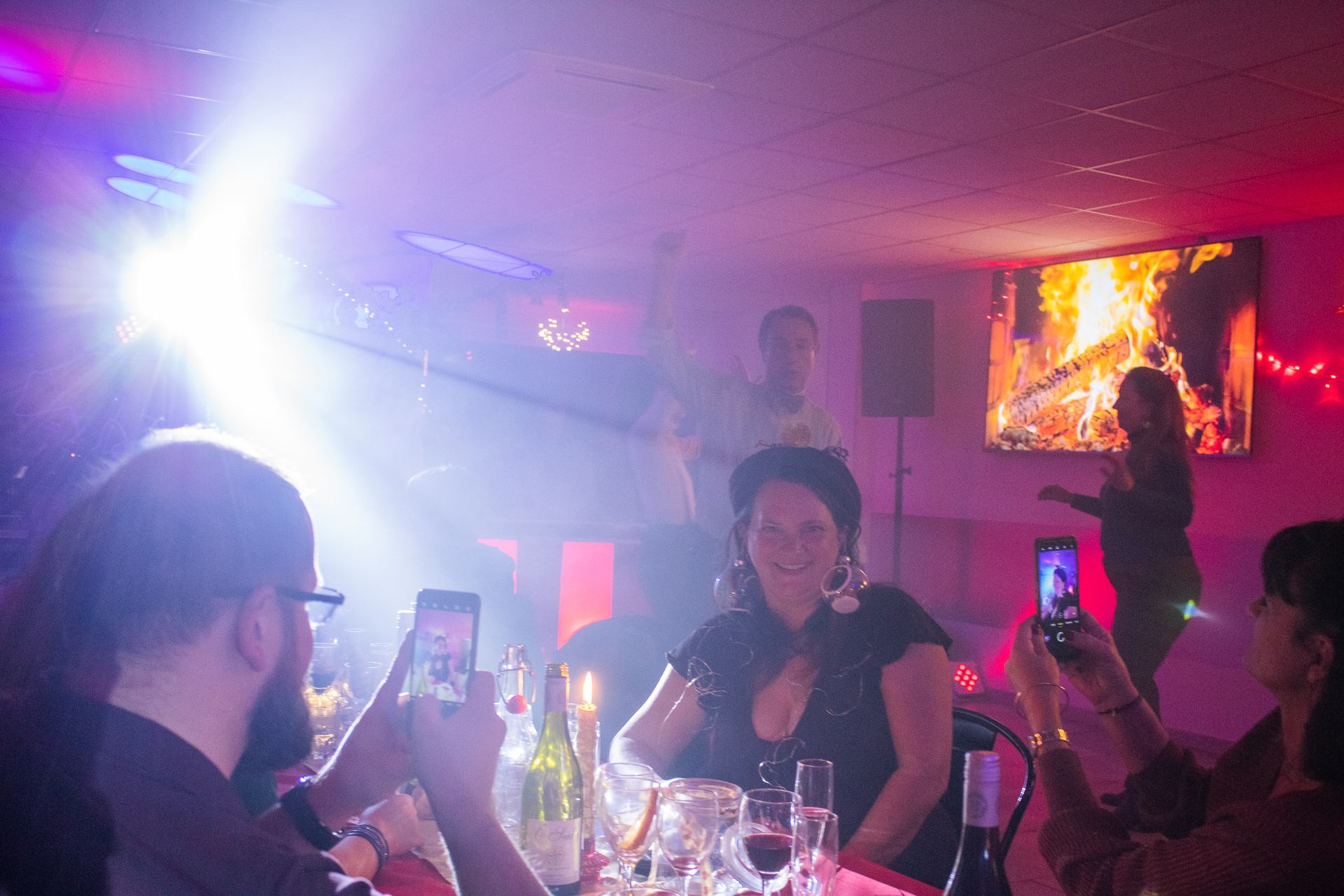 Soirée Prestige 2022 à Montpellier : invités photographiant la soirée avec leur téléphone, flash lumineux et écran décoratif en arrière-plan.