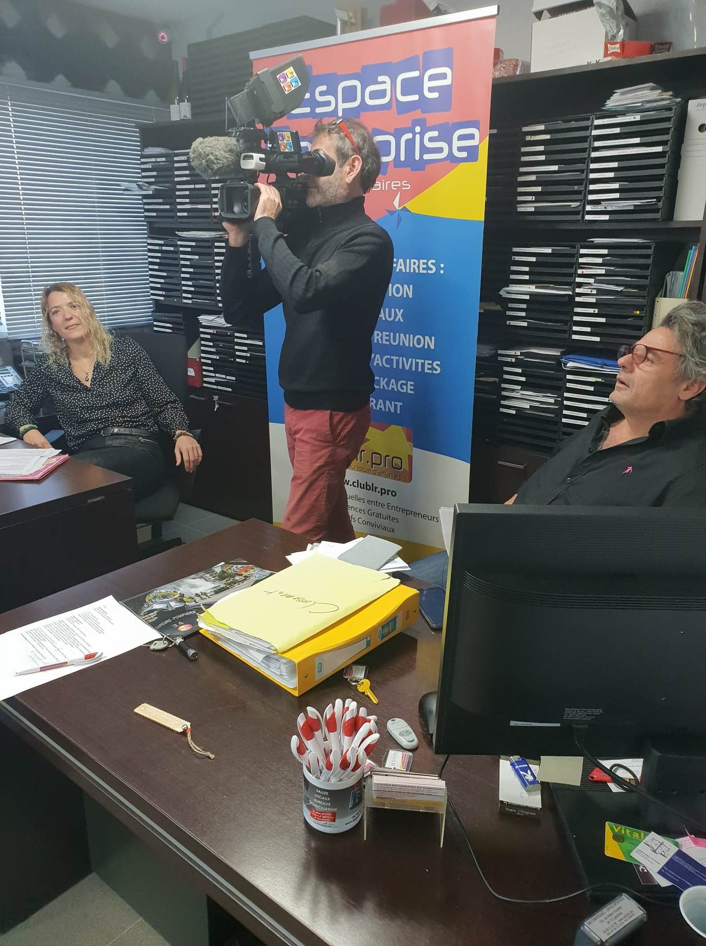 Vœux 2019 Espace Entreprise à Montpellier : tournage du clip de vœux, cadreur filmant une collaboratrice au bureau pendant que Nicolas observe la scène.
