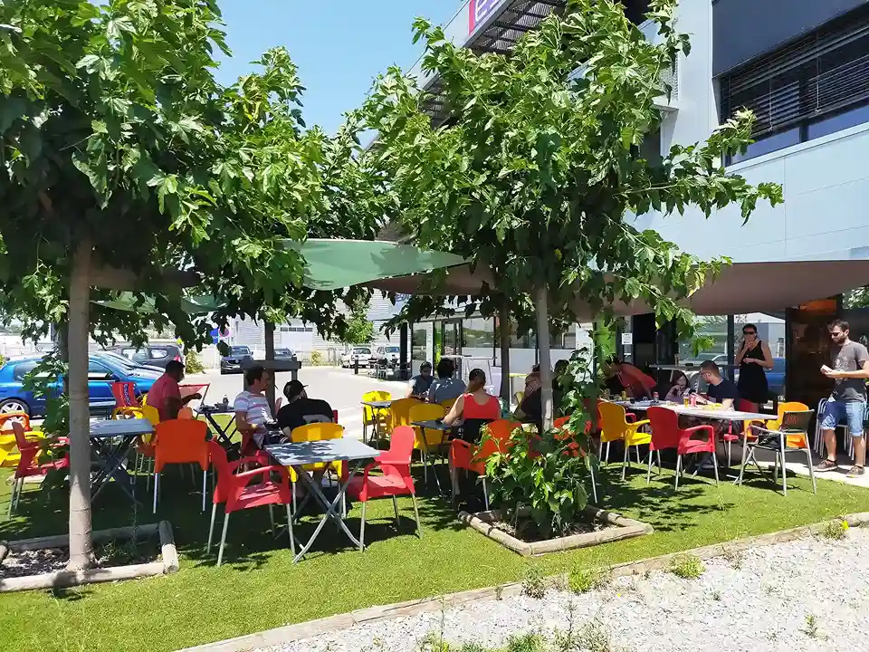 Terrasse ombragée d'Espace Entreprise Garosud à Montpellier, tables et parasols sous les arbres