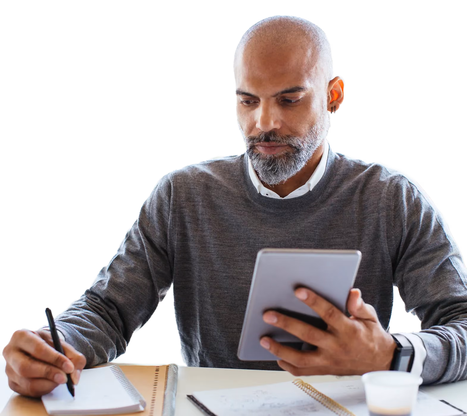 Homme prenant des notes devant une tablette et un carnet à son bureau
