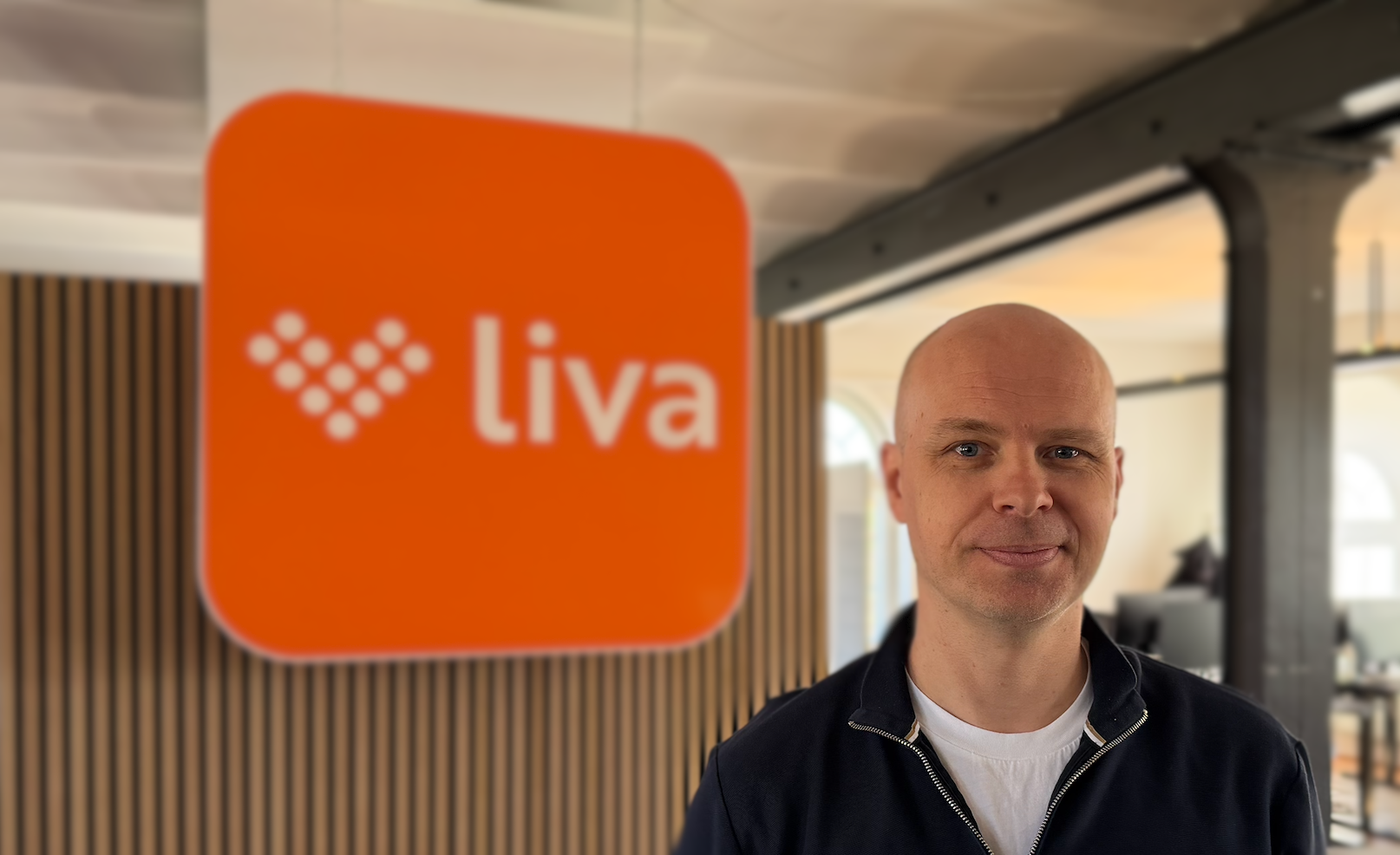 man standing in front of Liva logo