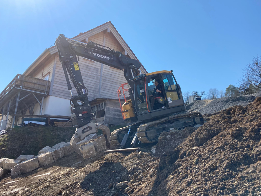 Bagger vor Gebäude auf Erdboden