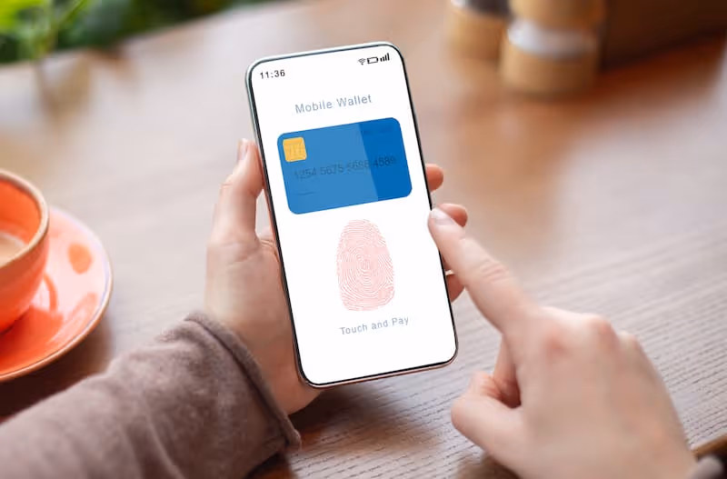Person holding smartphone displaying mobile wallet app with fingerprint icon for touch and pay.