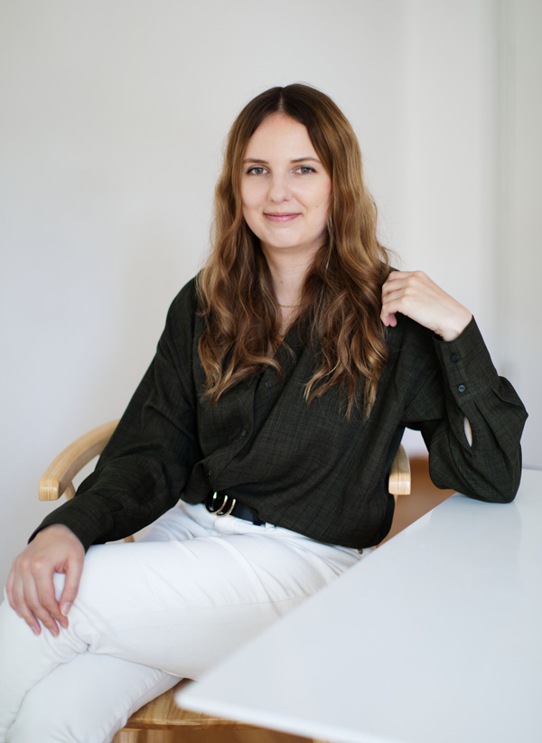 Foto von mir, wie ich an einem Tisch sitze und in die Kamera schaue