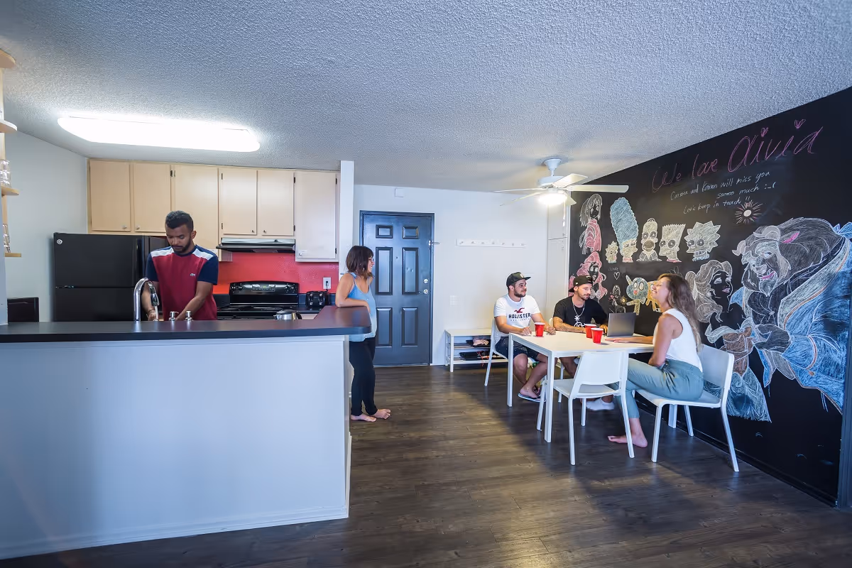 International students cooking together and practicing English in shared apartment abroad (2026 immersion trend)