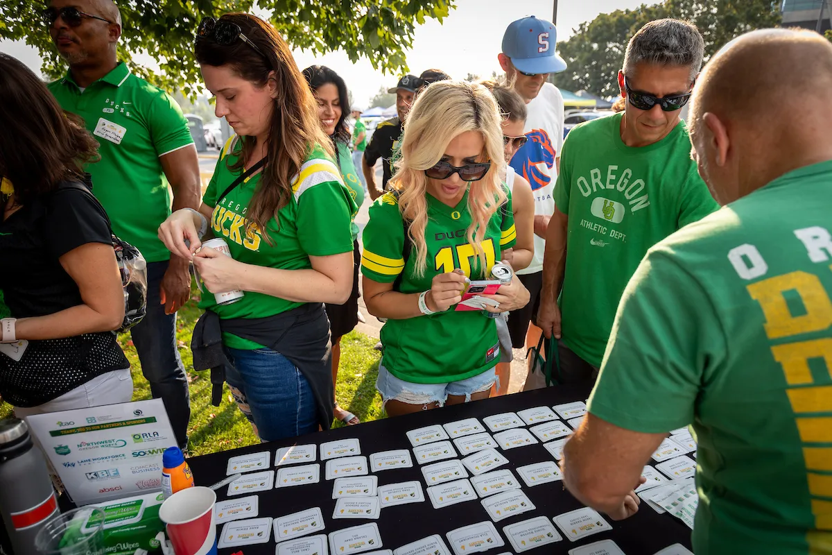 A group of people in green shirts gathered around a table, creating name tags for themselves.