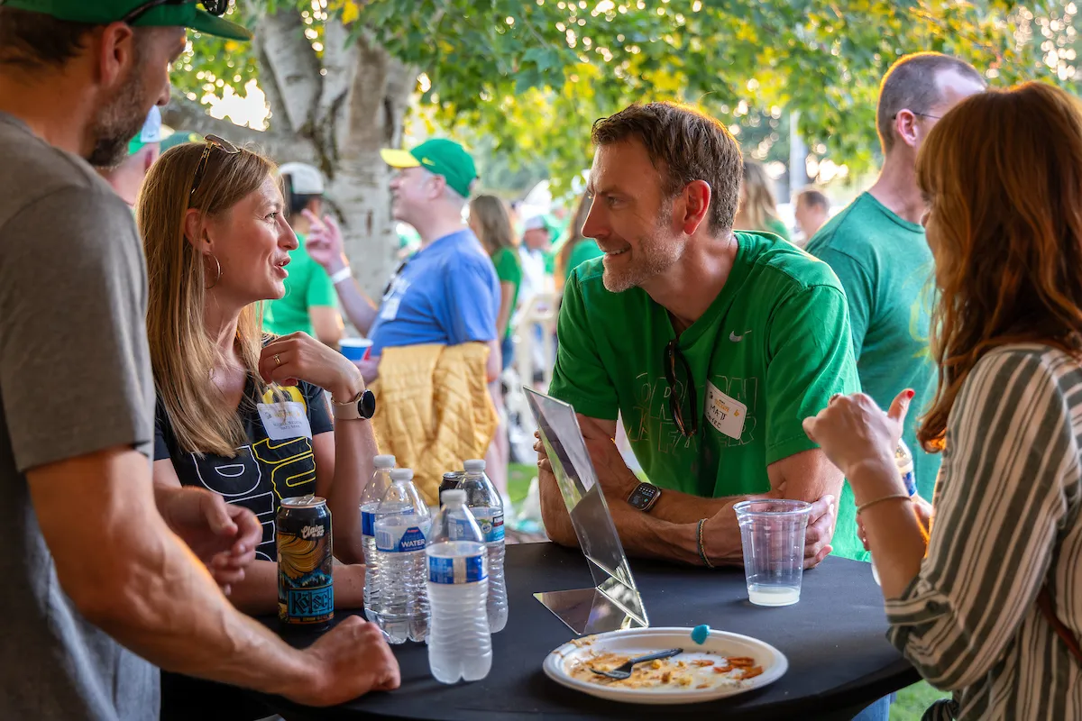People gathered around a table, talking after eating their food.
