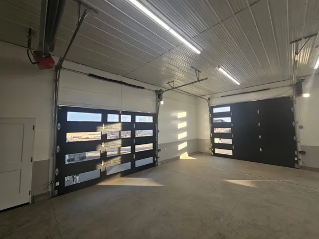 Complete Door Solutions – unique interior glass garage door opening to outdoor patio space.