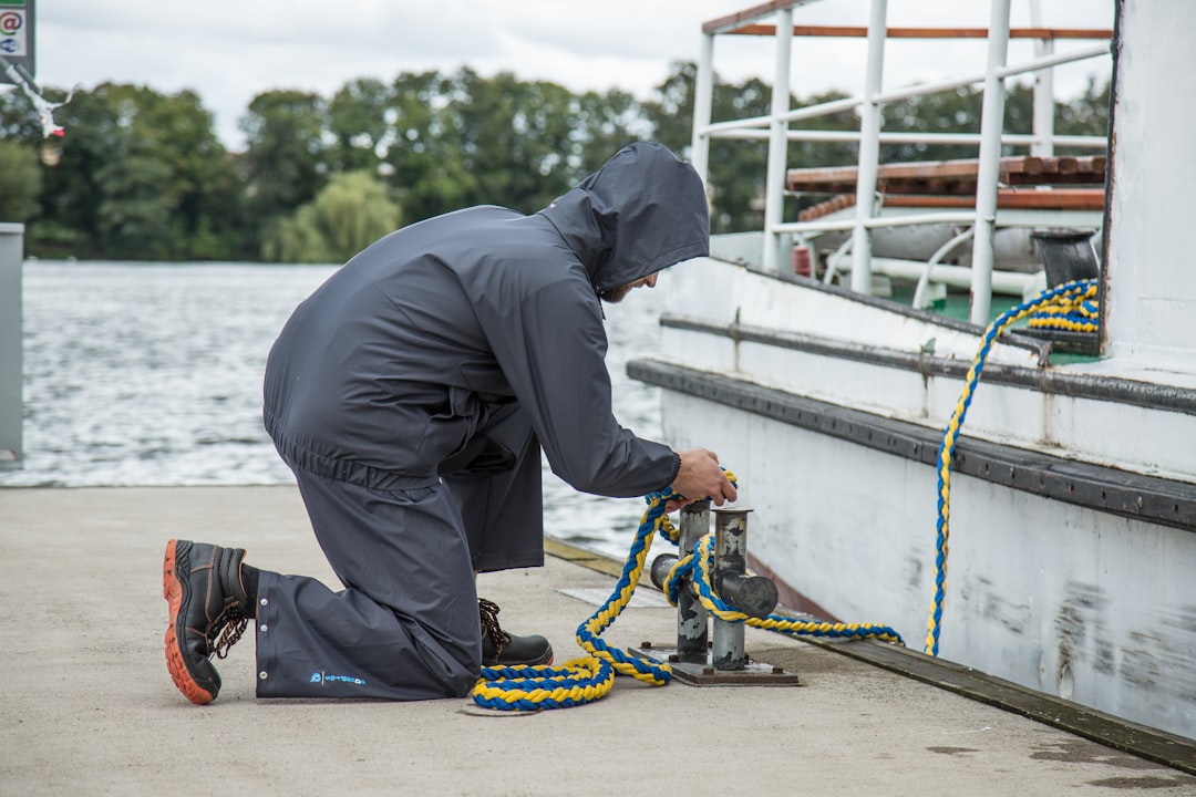 A person inspecting a floating dock's anchor chain connection, checking for wear and corrosion - floating dock tie downs A person inspecting a floating dock's anchor chain connection, checking for wear and corrosion - floating dock tie downs